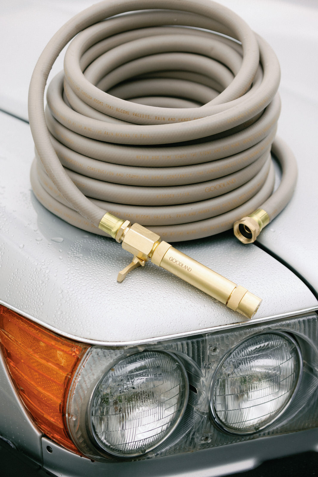 Coiled gray garden hose with brass nozzle on top of a car