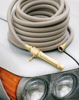Coiled gray garden hose with brass nozzle on top of a car