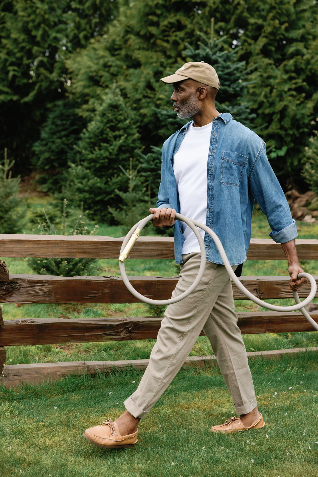 Man walking and holding a long grey garden hose from Goodland