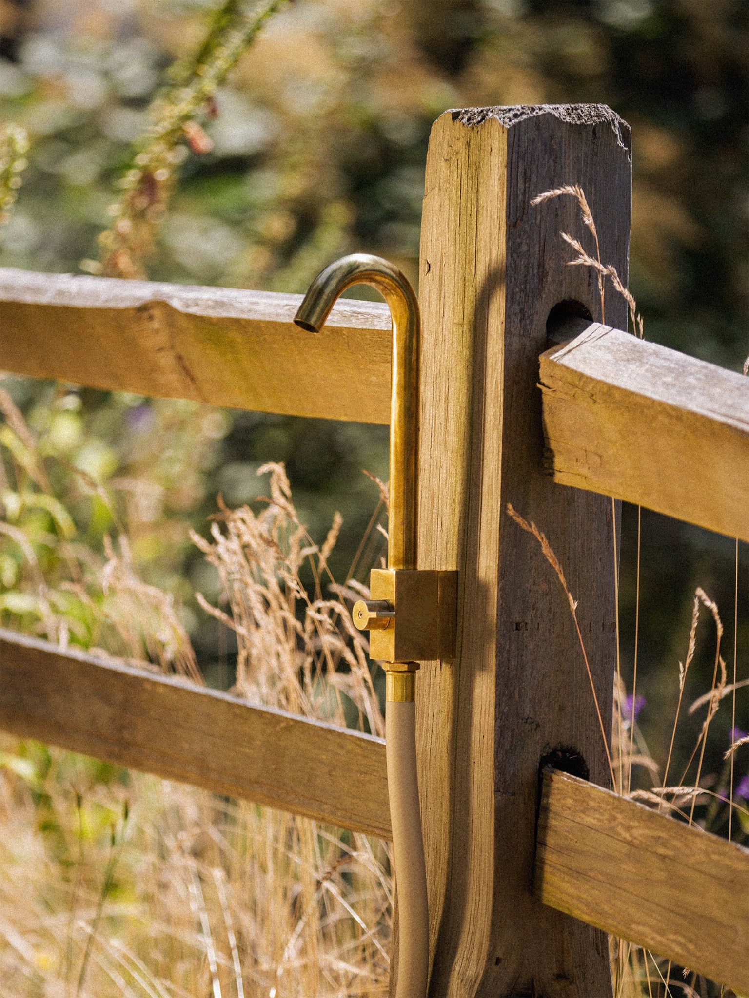 brass outdoor faucet on fence post attached to garden hose