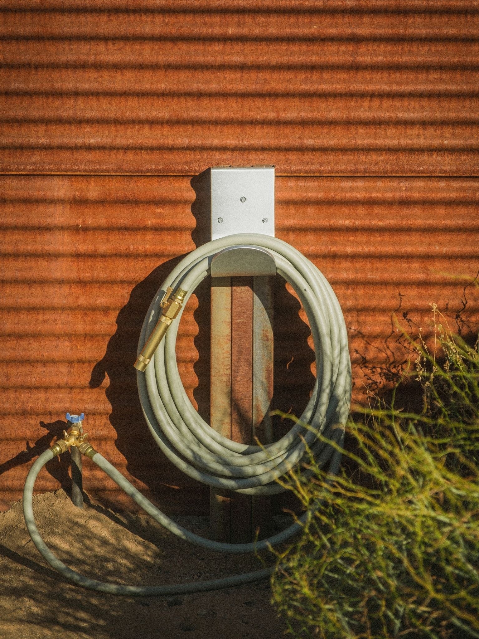 Luxury green garden hose with brass fittings that's made in Canada on wall mounted hose hanger