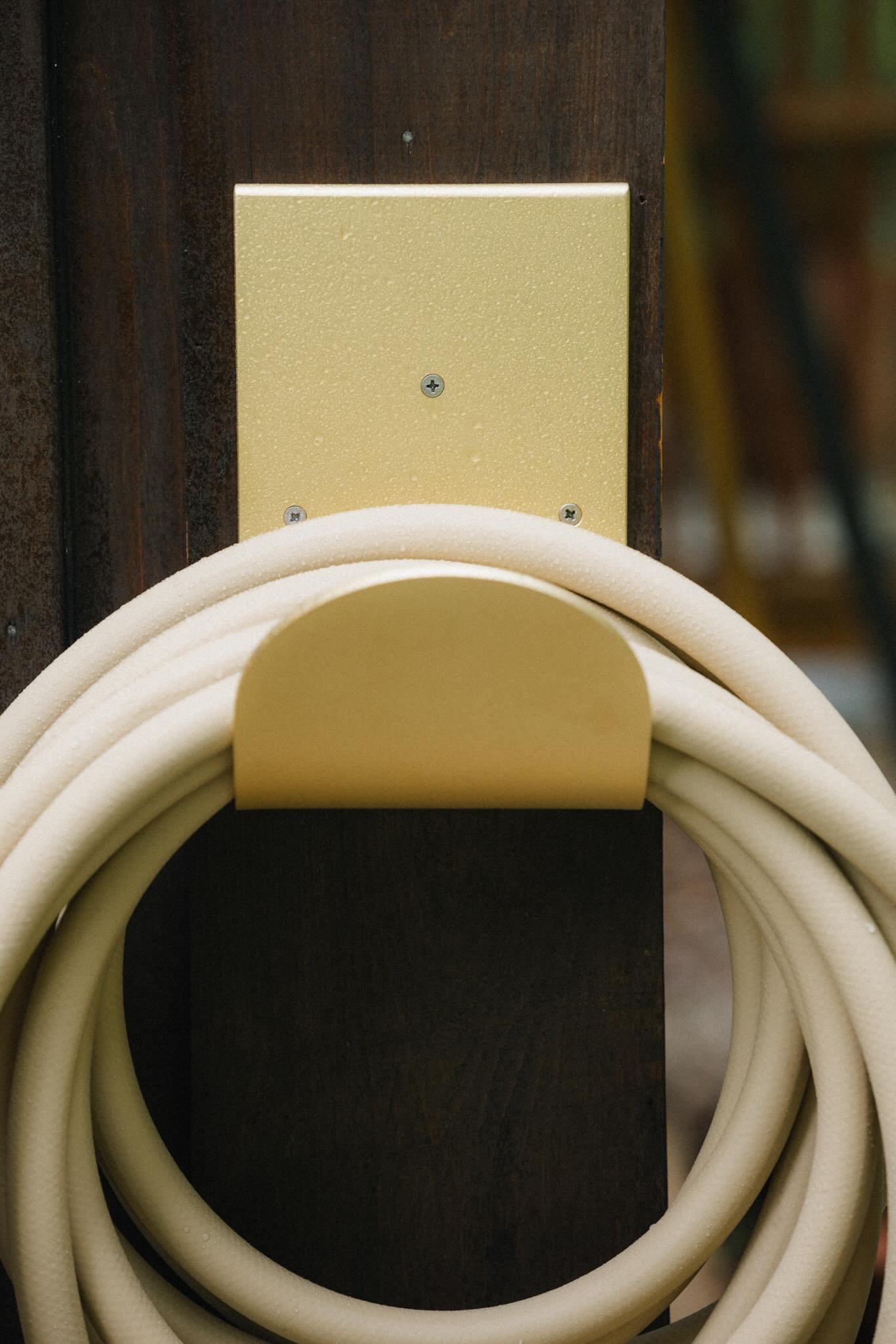 metal hose hanger in brass with garden hose