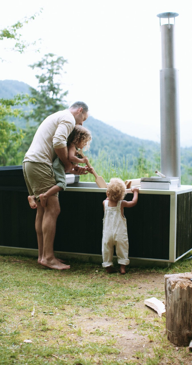 Goodland hot tub in black - dad and kids mixing the water 
