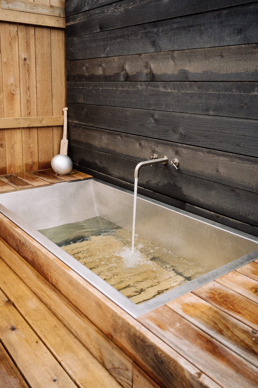 Stainless steel soaking tub with red cedar built into outdoor space