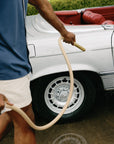Man watering car with tan luxury garden hose