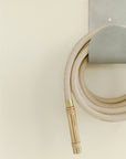 Solid brass hose nozzle on tan garden hose with wall mounted hose hanger 