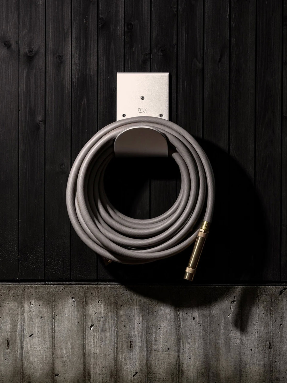 Metal hose holder wall mount with grey garden hose
