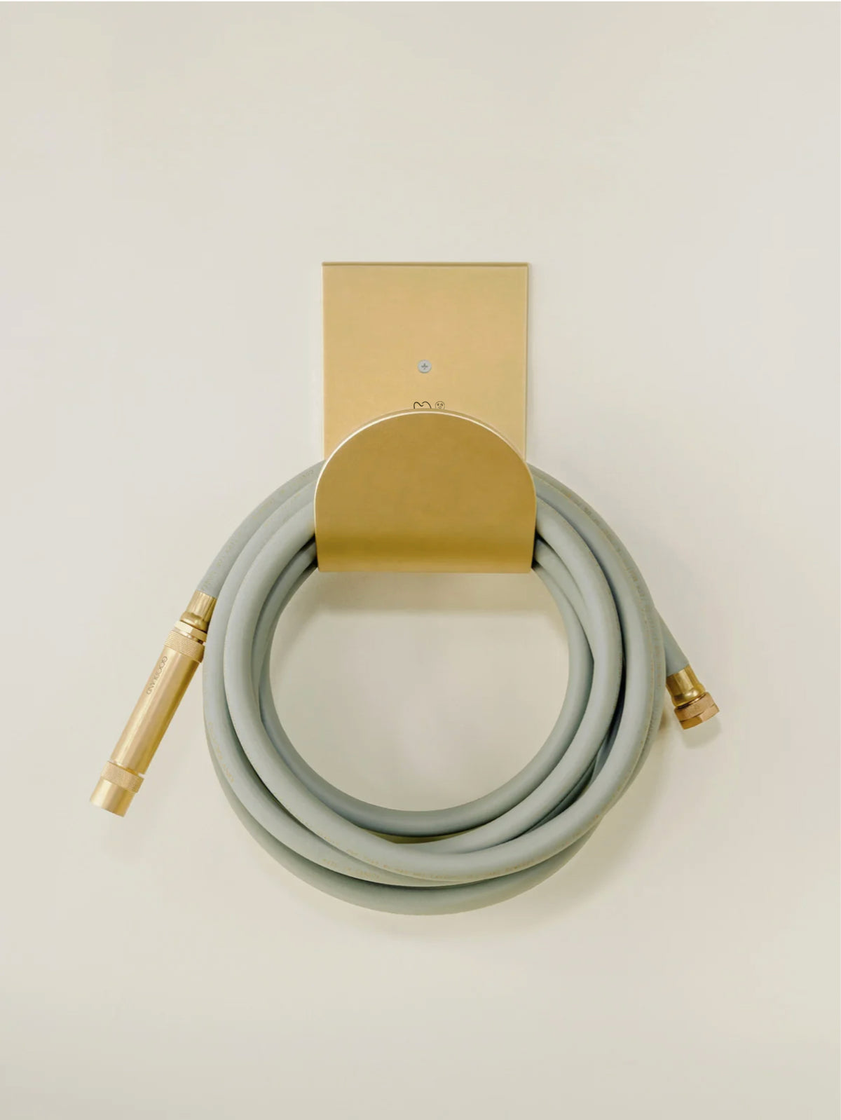 Modern brass hose holder in raw brass with garden hose coiled #color_raw_brass