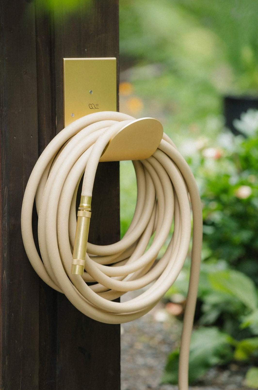 Hose hanger in raw brass with garden hose