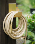 Hose hanger in raw brass with garden hose 