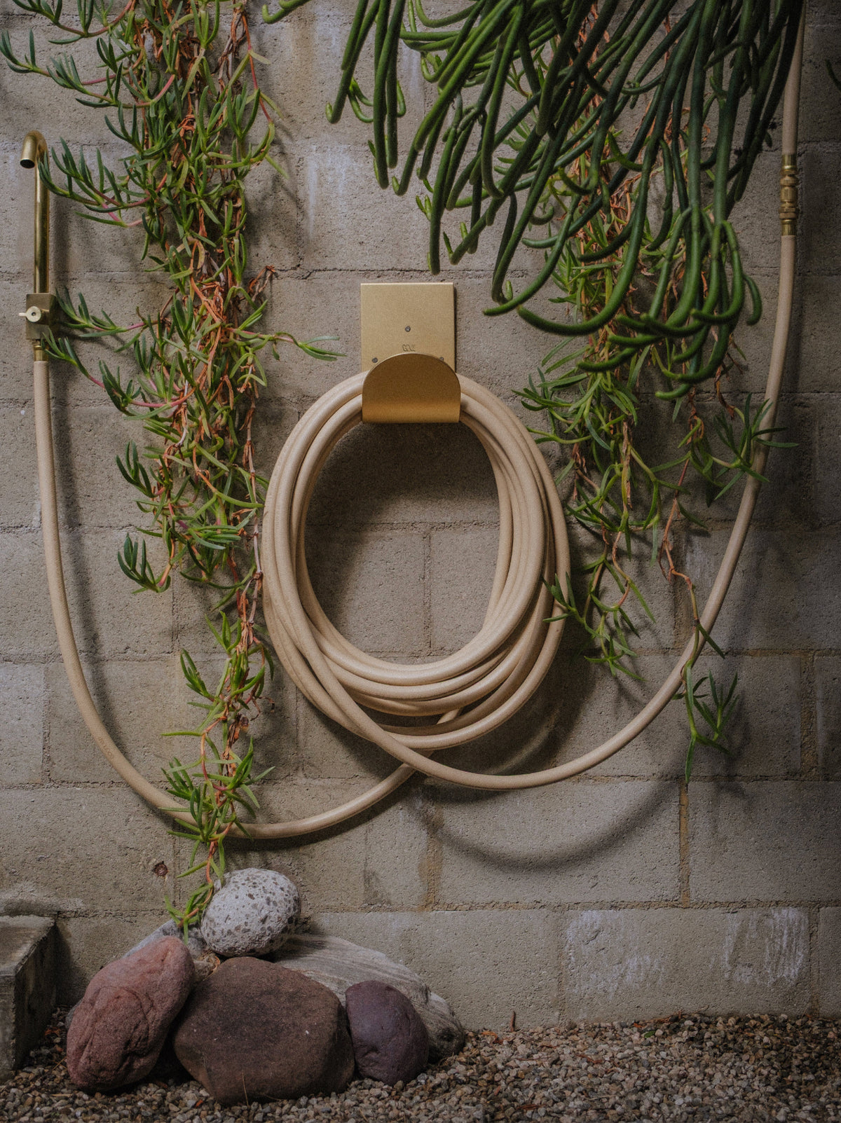 Wall mount hose holder in brass with water hose in garden