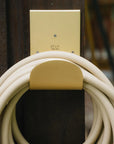Metal wall mounted hose hanger in brass with garden hose 
