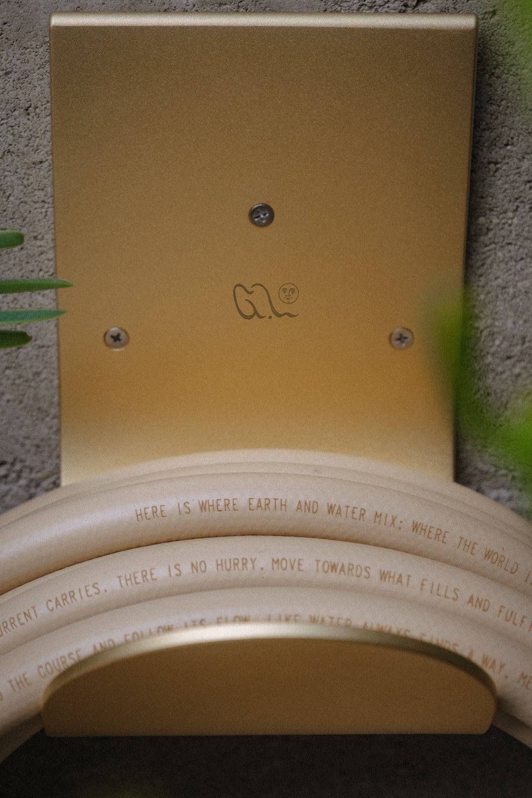 Brass garden hose hook with a tan garden hose